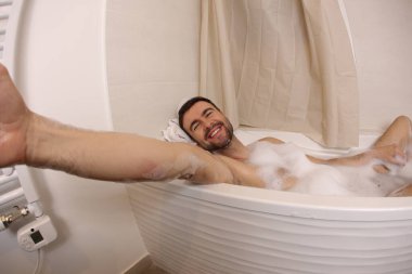 wide angle shot of handsome young man talking selfie in bath