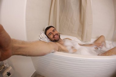 wide angle shot of handsome young man talking selfie in bath