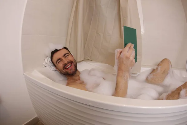 お風呂の中で本を読んでいるハンサムな若い男の広角ショット — ストック写真