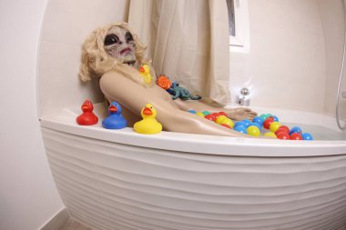 wide angle shot of mannequin with alien head in bath tub
