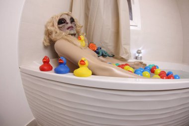 wide angle shot of mannequin with alien mask in bath tub