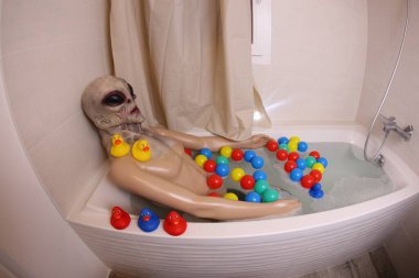 wide angle shot of mannequin with alien mask in bath tub