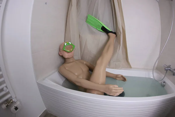 wide angle shot of mannequin with snorkeling mask and flippers in bath tub