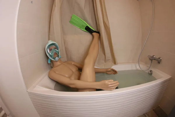 wide angle shot of mannequin with snorkeling mask and flippers in bath tub