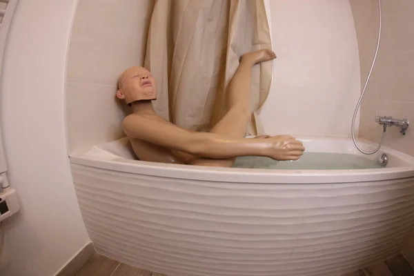 wide angle shot of mannequin with crying baby mask in bath tub