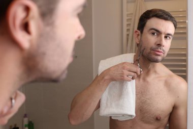 Banyoda aynanın önünde sakal kesen yakışıklı genç adamın portresi.