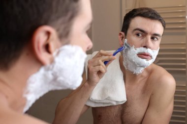 Banyoda aynanın önünde tıraş olan yakışıklı bir gencin portresi.