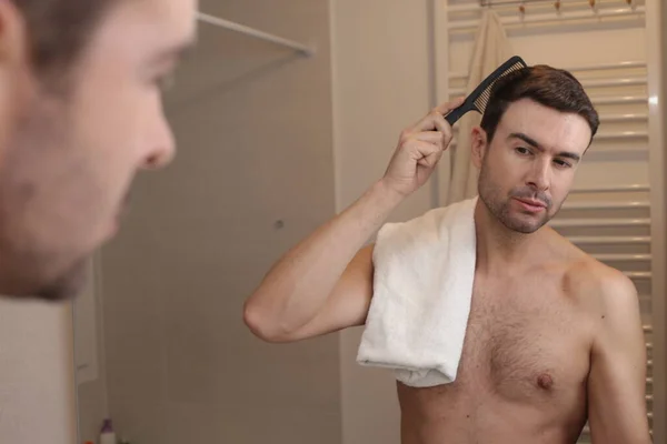 浴室の鏡の前で髪をブラッシングしているハンサムな若い男の肖像画 — ストック写真