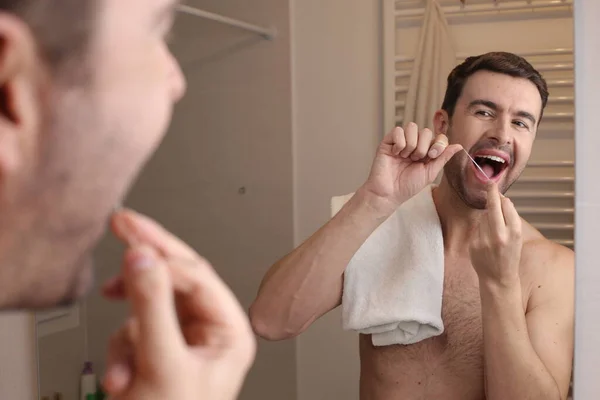 浴室の鏡の前で歯のフロスを使うハンサムな青年の肖像画 — ストック写真