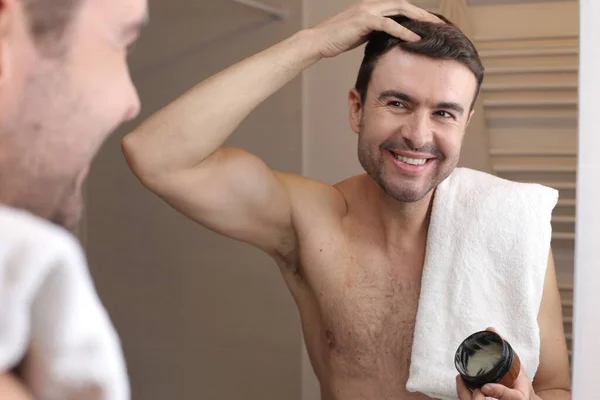 浴室の鏡の前でヘアスタイルのバームを適用するハンサムな若い男の肖像画 — ストック写真