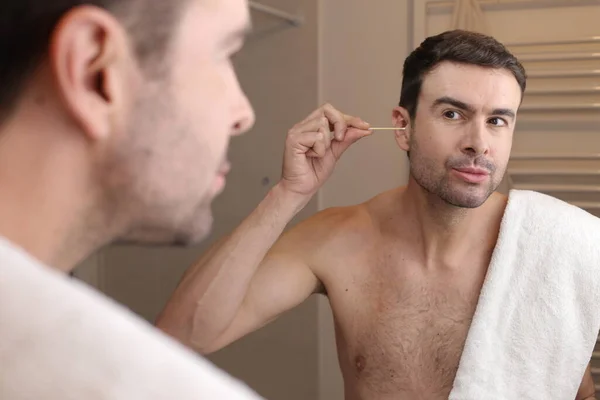 ハンサムな若い男の肖像画バスルームの鏡の前に綿棒で耳を掃除 — ストック写真