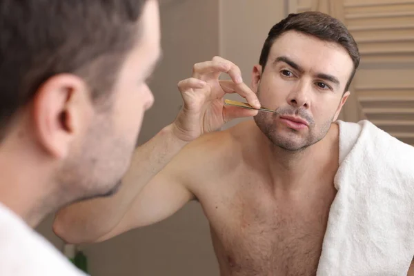 ハンサムな若い男の肖像画は バスルームで鏡の前にピンセットで口ひげを抜く — ストック写真