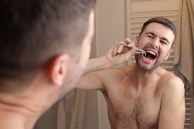 Banyoda aynanın önünde dişlerini söken yakışıklı bir gencin portresi.