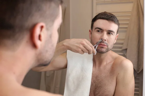 浴室の鏡の前で鼻毛をトリミングするハンサムな若い男の肖像画 — ストック写真