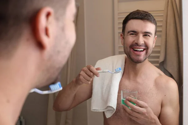 浴室の鏡の前に歯ブラシとタオルを持ったハンサムな青年の肖像画 — ストック写真