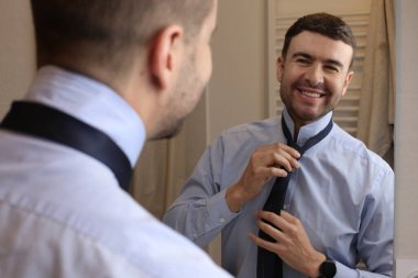 Banyoda aynanın önünde gömleği ve kravatı olan yakışıklı bir genç adam portresi.