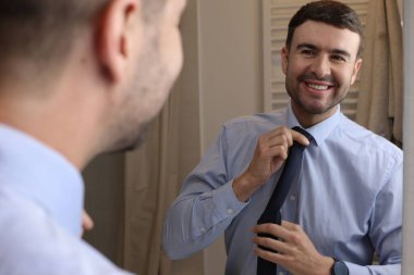 Banyoda aynanın önünde gömleği ve kravatı olan yakışıklı bir genç adam portresi.