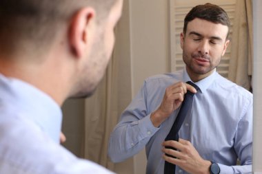 Banyoda aynanın önünde gömleği ve kravatı olan yakışıklı bir genç adam portresi.