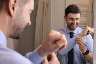 Banyoda aynanın önünde gömleği ve kravatı olan yakışıklı bir genç adam portresi.