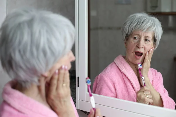 浴室里在镜子前刷牙的成熟女人的特写 — 图库照片