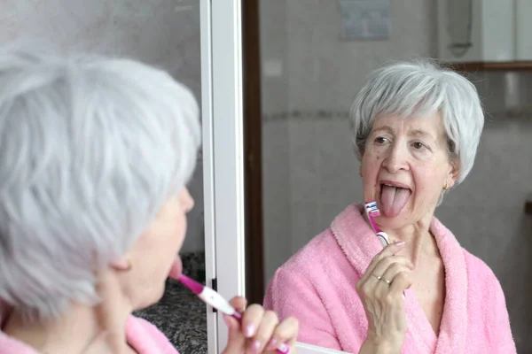 Portret Dojrzałej Kobiety Myjącej Zęby Przed Lustrem Łazience — Zdjęcie stockowe