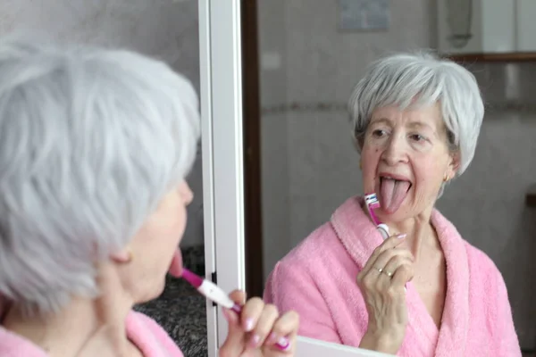 浴室里在镜子前刷牙的成熟女人的特写 — 图库照片