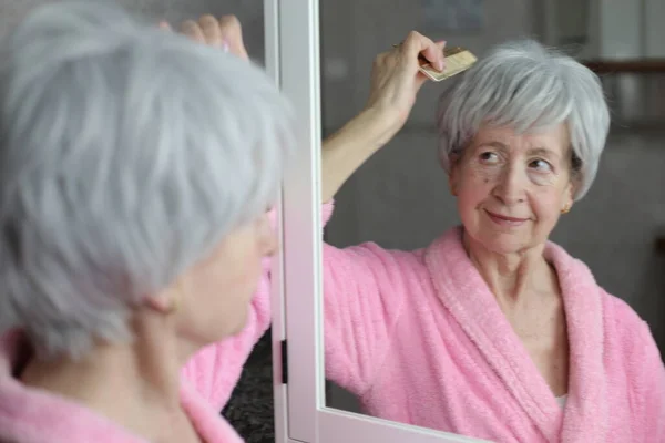 stock image close-up portrait of mature woman brushing hair in front of mirror in bathroom