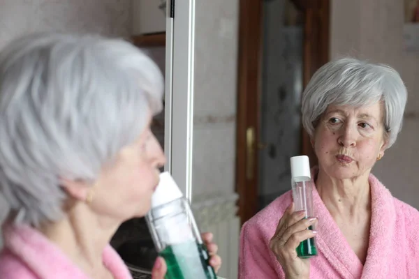 Närbild Porträtt Mogen Kvinna Med Flaska Munvatten Framför Spegeln Badrummet — Stockfoto
