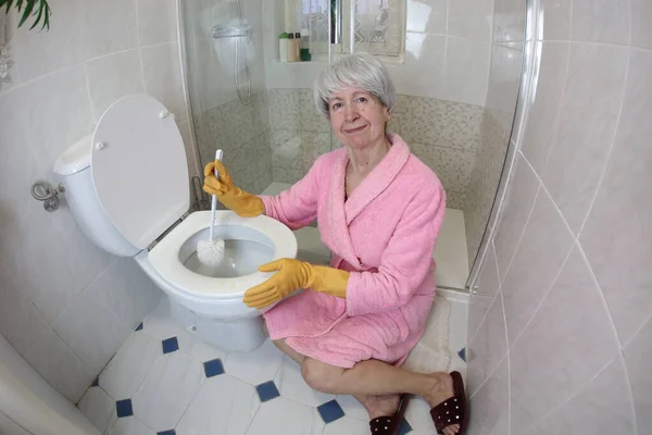 老年妇女清洁厕所的广角镜头 — 图库照片