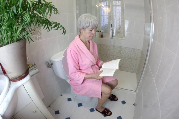 老年妇女在厕所看书的广角镜头 — 图库照片