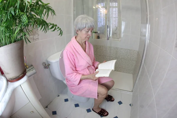 老年妇女在厕所看书的广角镜头 — 图库照片