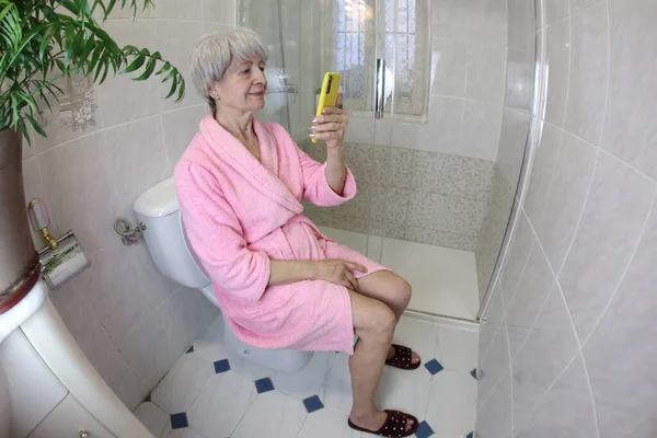 トイレでスマホを使う先輩女性の広角撮影 — ストック写真