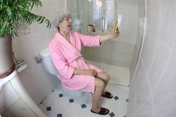 老年妇女坐在浴室厕所时自拍的广角镜头 — 图库照片