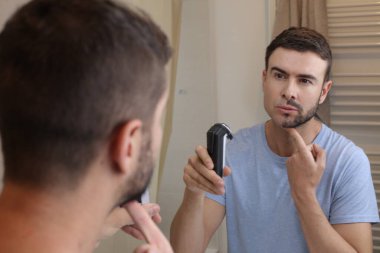 Banyoda aynanın önünde yarı tıraşlı sakallı yakışıklı genç adamın portresi.