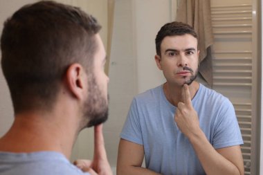 Banyoda aynanın önünde yarı tıraşlı sakallı yakışıklı genç adamın portresi.