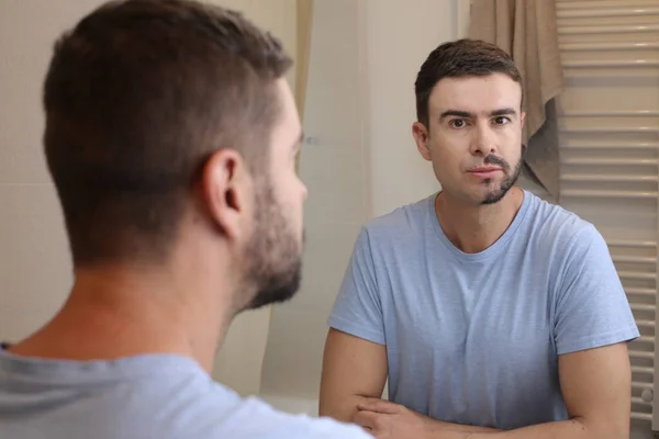 stock image portrait of handsome young man with half shaved beard in front of mirror in bathroom