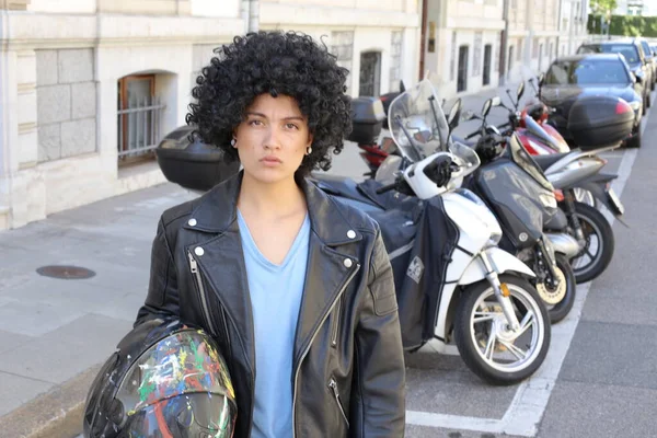街の通りに駐車自転車の前に巻き毛のある革のジャケットの美しい若い女性の肖像画 — ストック写真