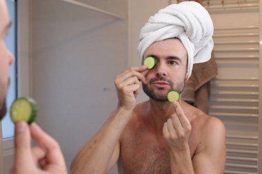 Kafasında havluyla genç bir adamın portresi ve banyoda aynanın önünde salatalıklar.