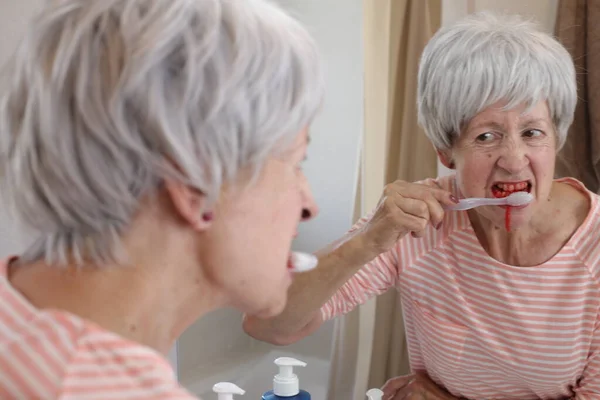在浴室的镜子前刷牙时 用牙龈出血的成熟女人的特写肖像 — 图库照片