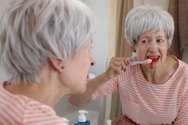 Portret Dojrzałej Kobiety Krwawiącymi Dziąsłami Podczas Mycia Zębów Przed Lustrem — Zdjęcie stockowe