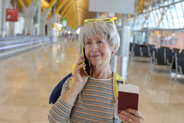 空港で電話で話すパスポートを持つ成熟した女性のクローズアップ肖像画 — ストック写真