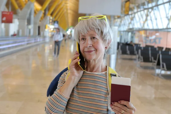 空港で電話で話すパスポートを持つ成熟した女性のクローズアップ肖像画 — ストック写真