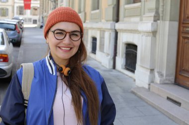 Şehir caddesinde, şık hippi kıyafetleri içinde, klasik kulaklıklı güzel bir kadının portresi.