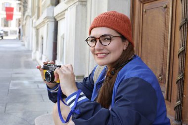 Şık hippi elbiseli, klasik kulaklıklı ve şehir caddesinde film kamerası olan güzel bir kadının portresi.