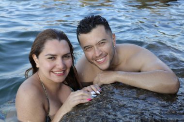 Kayalık deniz kıyısında birlikte poz veren genç bir çiftin yakın plan portresi.