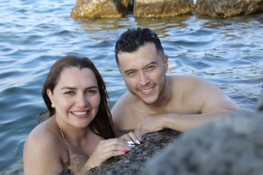 Kayalık deniz kıyısında birlikte poz veren genç bir çiftin yakın plan portresi.