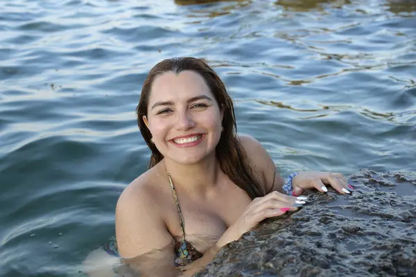 ロッキー海岸で水にポーズするビキニの美しい若い女性のクローズアップポートレート — ストック写真