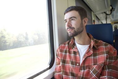 Trenle seyahat eden yakışıklı genç adamın portresi.