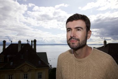 Eski Avrupa kasabasında gezen yakışıklı, mutlu genç adamın portresi.