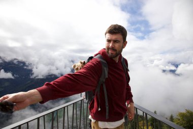 Sırt çantasında sevimli köpeğiyle gezen yakışıklı, mutlu genç adamın portresi.